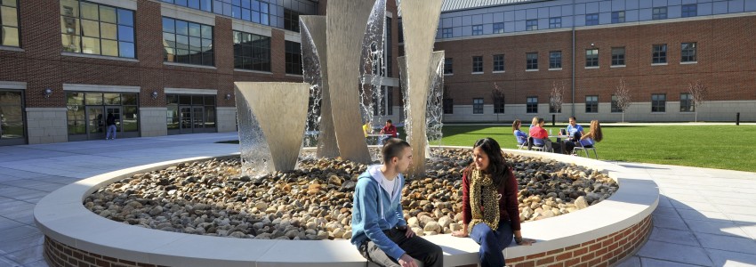 students sitting next to a fountain at the Waterbury campus